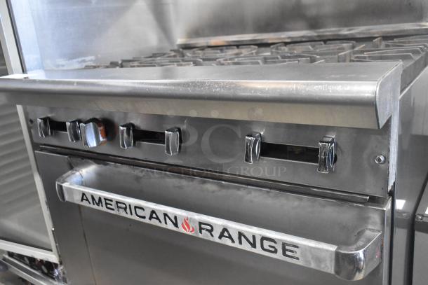 American Range stainless steel commercial range with 6 burners, oven, overshelf, and backsplash on casters. Good condition.