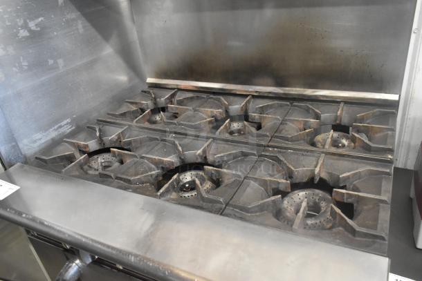 American Range stainless steel 6 burner commercial range, with oven, over shelf, backsplash, and commercial casters.