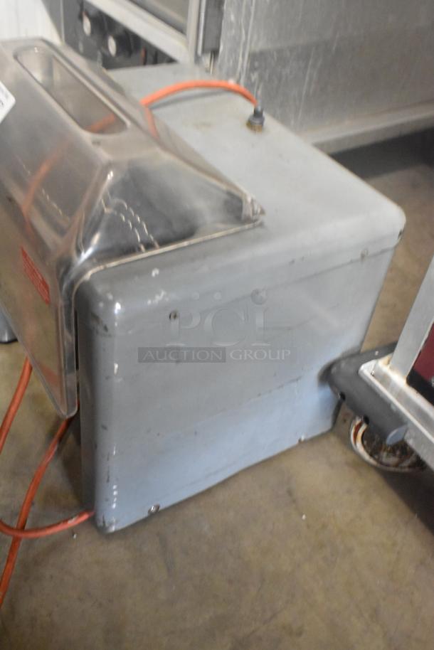 Metal commercial countertop electric meat tenderizer, 115 volts, 1 phase, with a clear plastic cover. Visible wear on the surface.
