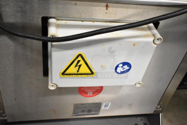 Stainless steel JBT 2ND-GEN-MFJ-HE citrus juicer with safety labels, commercial casters, 115V, 1 phase.