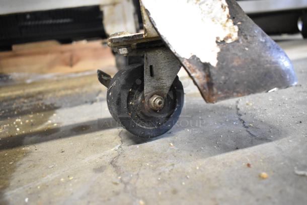Close-up of a caster wheel on the Oliver 797-32NC bread loaf slicer, showing slight wear and some bread crumbs.