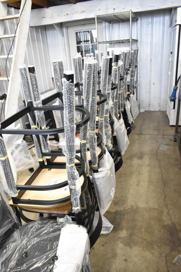 14 new Lancaster Table & Seating cross-back bar stools with black finish and vintage wood seats, wrapped in protective packaging.