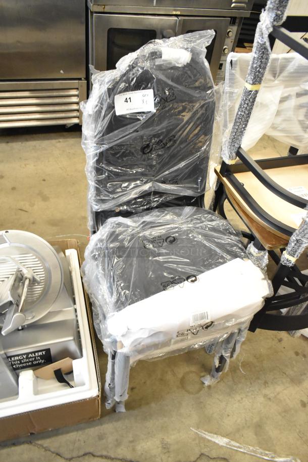 Stacked Lancaster Table & Seating black banquet chairs, new with packaging, featuring 2" padded seat and silver vein frame.