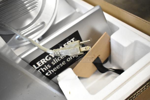 Bizerba metal commercial countertop meat slicer, 115 volts, 1 phase, in box with power cord and caution label visible.