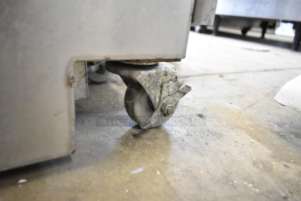 Metal fryer oil caddy on commercial casters, showing a close-up of the caster wheel. Condition appears used. 115/230 volts, 1 phase.