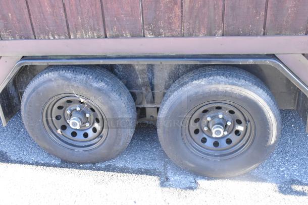 Dual-axle wheel section of a fully outfitted food trailer, showcasing sturdy tires and metal rims.