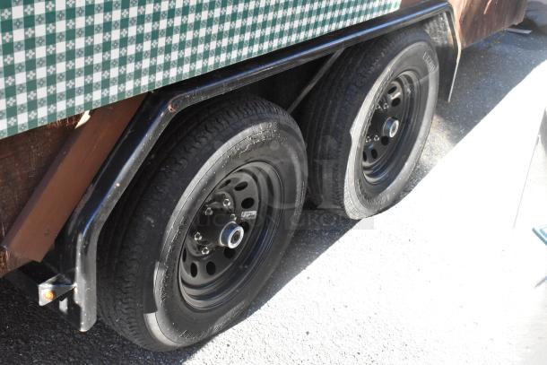 Dual axle food trailer with patterned exterior. Sturdy wheels in good condition, suitable for mobile kitchen setup.