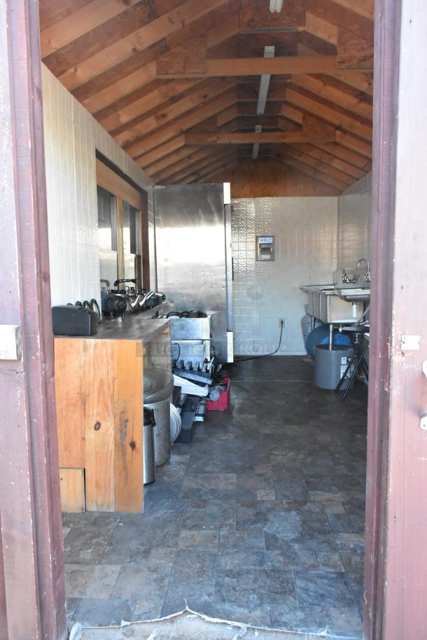 Fully equipped food trailer interior with commercial appliances, including Avantco cooler, steam table, and sinks. Ready to use.