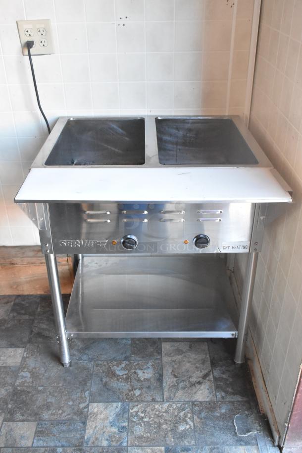 ServIt steam table with dual compartments, stainless steel, adjustable knobs, built-in shelf, used condition.