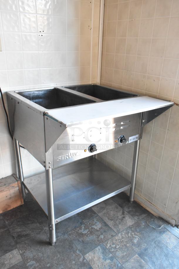 ServIt steam table in stainless steel, dual compartment, with temperature controls and shelf, located in a mobile kitchen setup.