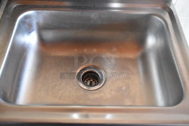 Stainless steel commercial sink with visible drain in a mobile kitchen food trailer. Clean and well-maintained.