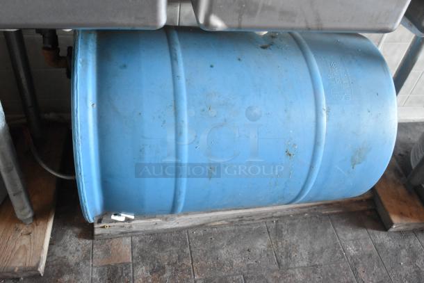 Blue plastic water tank used in a mobile food trailer. Visible wear suggests prior use. Mounted on a wooden base.