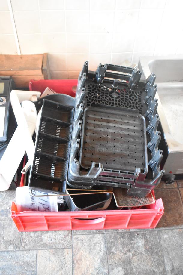 Red crate with assorted food service trays, utensils, and kitchen equipment parts, ideal for a mobile kitchen setup.
