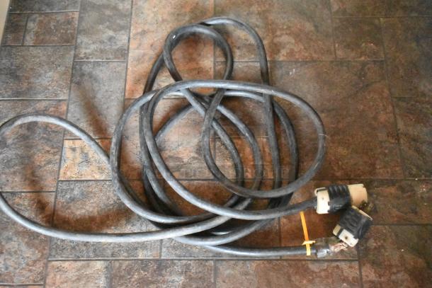 Coiled heavy-duty power cable with plug connectors on a tiled floor, part of mobile kitchen setup.