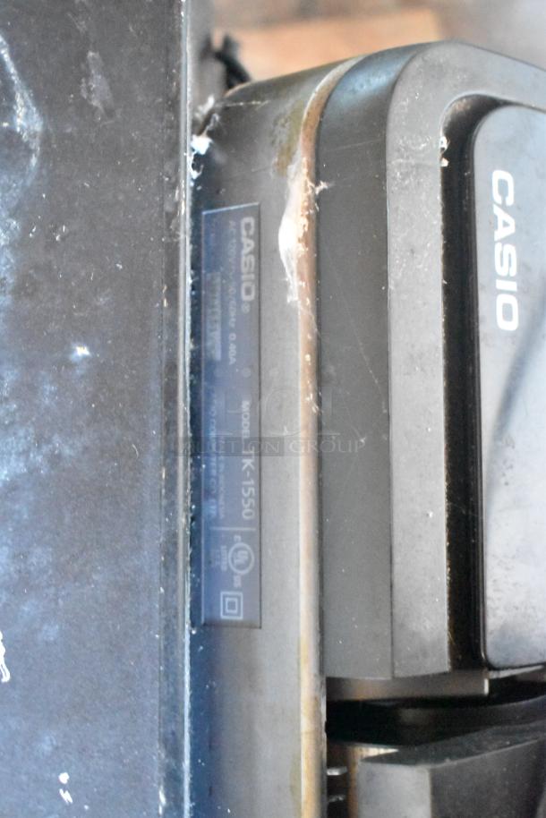 Casio model TK-1550 label on a commercial equipment piece, showing signs of use and wear.