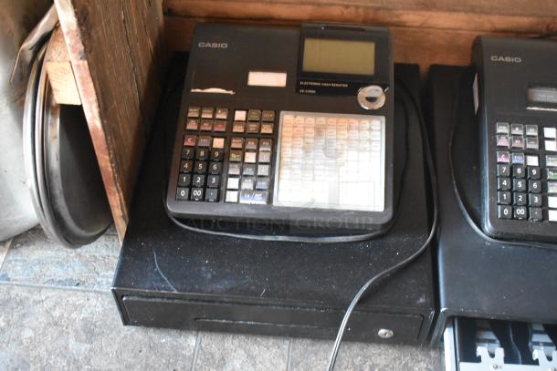 Casio electronic cash register with numeric keypad and display screen, showing wear, in a food trailer setting.