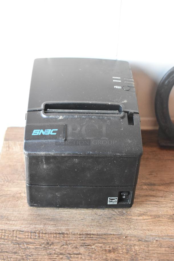 SNBC thermal receipt printer, black, with power, error, and feed buttons, used condition on a wooden surface.