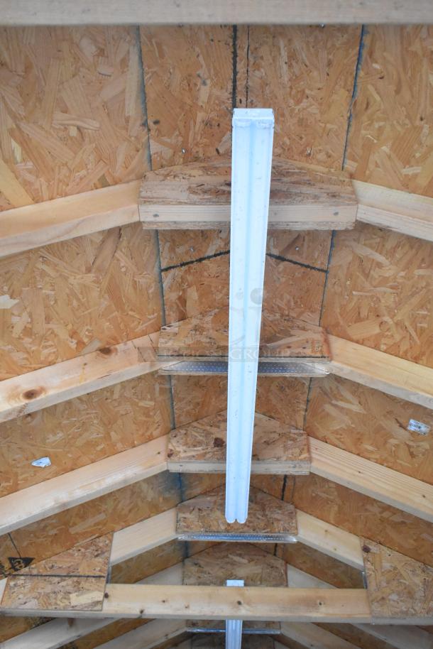 Interior roof of fully outfitted food trailer, showing wooden beams and fluorescent light fixture.