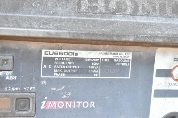 Close-up of Honda EU6500is generator label showing voltage, frequency, fuel type (gasoline), and output details.