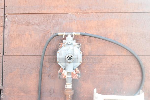 Gas regulator attached to the exterior of the 2007 Lanchester Mobile Kitchen. Hoses are connected for utility access.