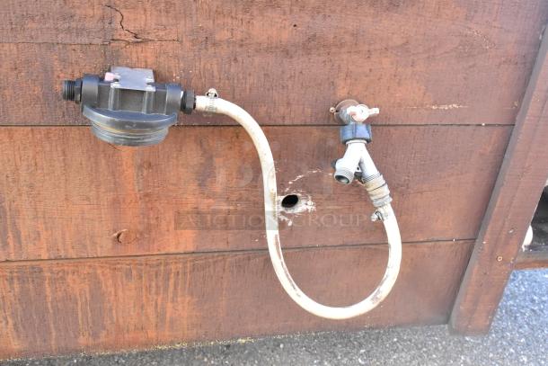 Exterior view of a 2007 Lanchester food trailer showing plumbing connections. Perfect for mobile kitchen setup.