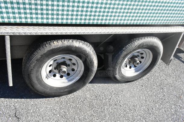 2007 Lanchester Trailer wheels, dual-axle, with a green-checkered siding. Visible tire tread and metal rim condition.