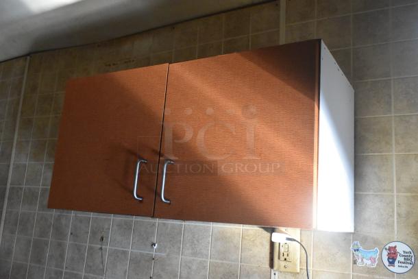 Wall-mounted kitchen cabinet inside a 2007 Lanchester food trailer. Wooden finish, metal handles, tiled backsplash.