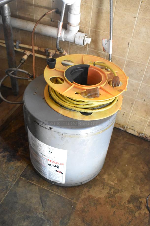 Yellow extension cord reel on top of a metal tank inside a 2007 Lanchester food trailer. Near tile wall and piping.