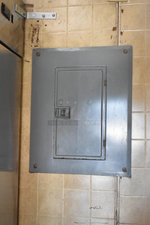 Electrical panel inside a 2007 Lanchester food trailer. Panel is closed and mounted on beige tiled wall.