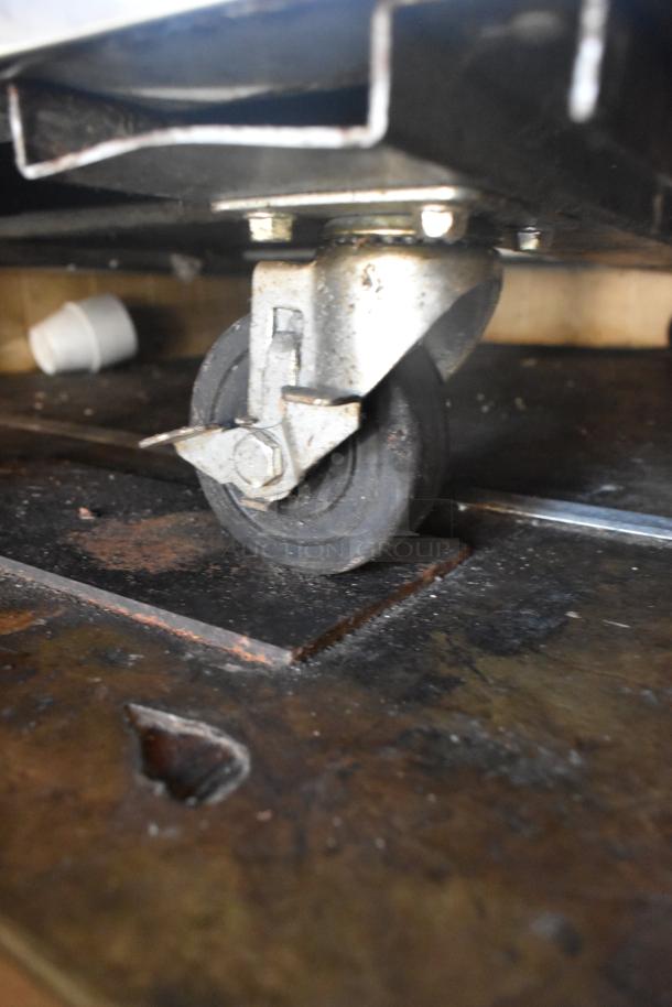 Close-up of a caster wheel on the 2007 Lanchester mobile kitchen trailer, showing wear and sturdy metal construction.