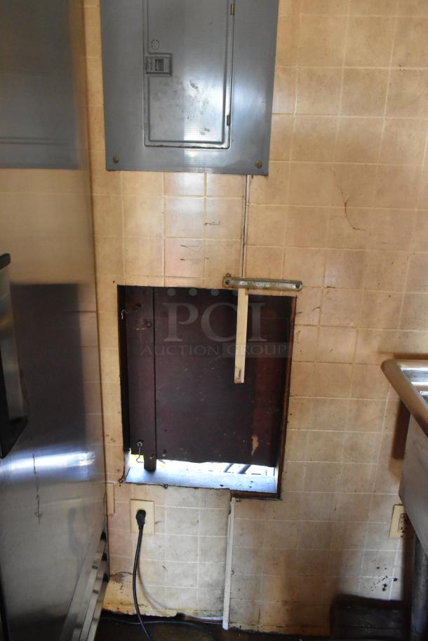 Interior detail of 2007 Lanchester food trailer showing a tiled wall with an electrical panel and access opening.