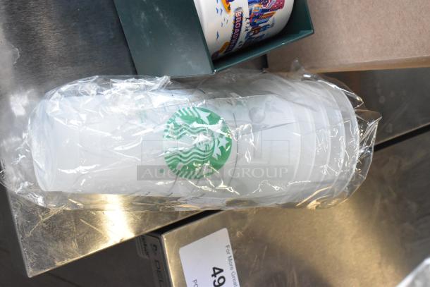 Lot of Starbucks items includes poly cups in packaging and ceramic mugs with city design. Good condition with visible logo.