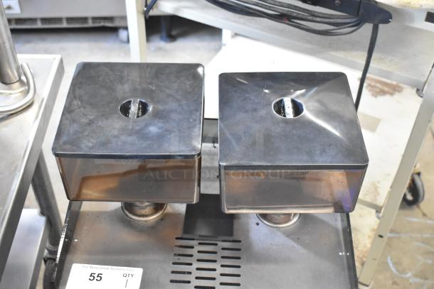 Schaerer Verismo 701 espresso machine with dual hoppers labeled "Regular" and "Decaf," metal countertop, used condition.
