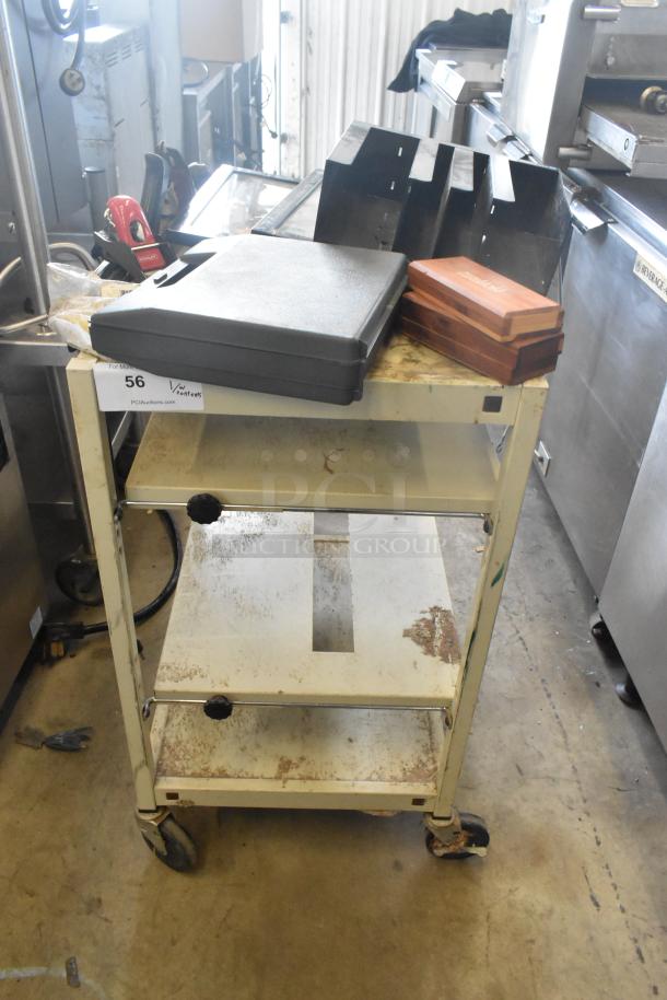 Metal 4 Tier Cart with commercial casters, showing signs of wear. Includes various items on top. Auction tag 56 visible.