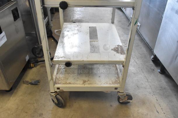 Metal 4-tier cart on commercial casters, showing signs of wear with rust and scratches. Ideal for industrial use.