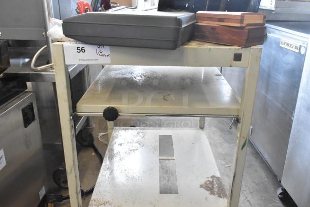 Metal 4-tier cart on commercial casters, used condition with visible wear. Includes label "56" from PCI Auctions.