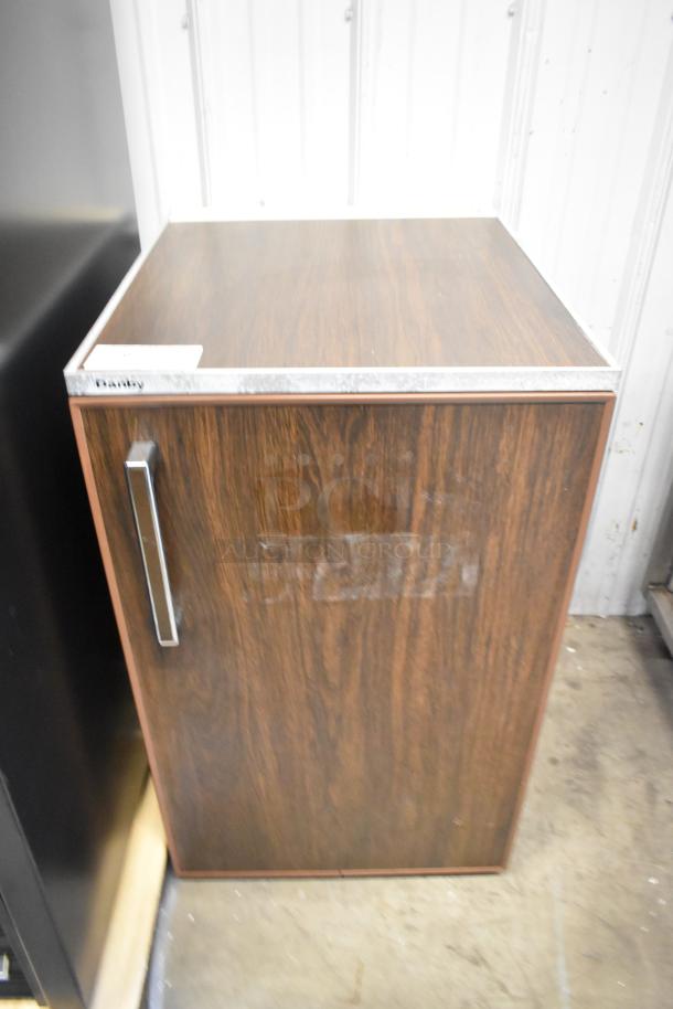 Danby Mini Cooler, wood finish. 115 volts, 1 phase. Features metal handle. Good condition. Danby label on top.