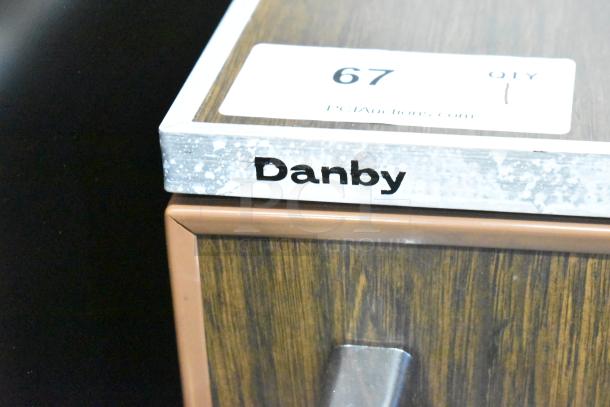 Danby Mini Cooler, 115V, 1 Phase. Brown wood finish, silver handle. Label with number 67 visible.