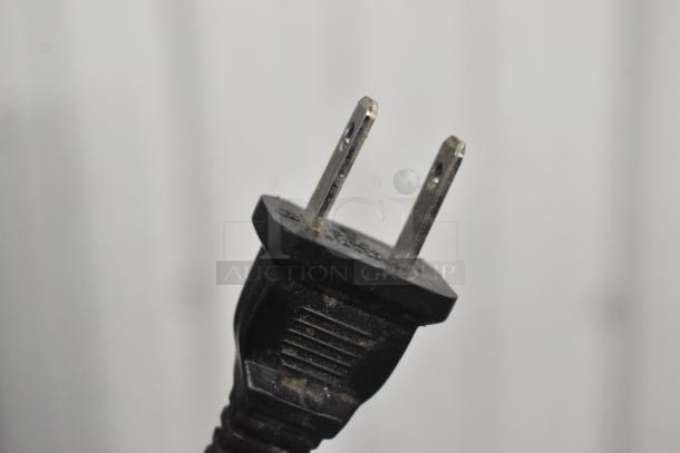 Close-up of a power plug for a Staples SPL-TXC12MA countertop shredder, showing prongs and black casing.