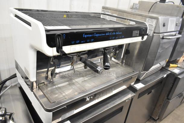 Faema Teorema stainless steel commercial 2-group espresso machine with 3 portafilters and 2 steam wands, on countertop.