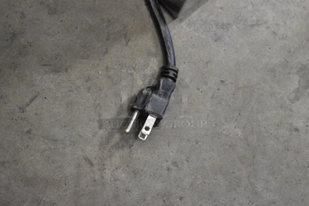 A close-up of a power plug for the 2019 Jun-Air 87R-4MN1-HSBHH Nitrogen Generator, visible on a concrete floor.