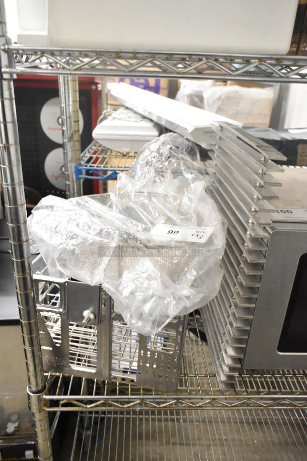 Three brand new items, including metal baskets and a grate, labeled as scratch and dent, on a storage shelf.