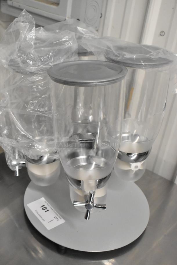 Brand new clear poly 4-hopper dry goods dispensing unit; one hopper with crack. Includes chrome spouts; item labeled 101.