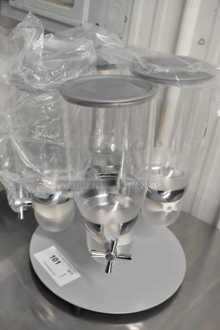 Brand new clear poly 4-hopper dry goods dispensing unit; one hopper with crack. Includes chrome spouts; item labeled 101.