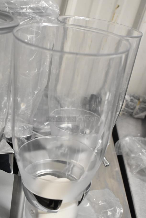 Clear poly 4-hopper dry goods dispenser, brand new, one hopper cracked, includes stainless steel accents, suitable for grains.