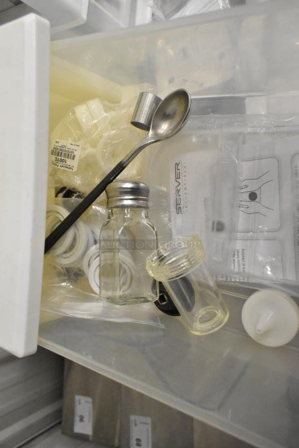 4 clear and white poly bins with contents including a metal spoon, glass jar, and plastic parts; good condition.