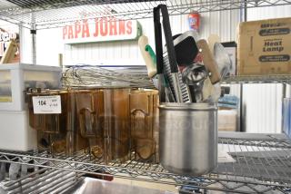 Lot of utensils and amber poly hoppers on a metal shelf. Includes whisks, spatulas, and various kitchen tools. Tag reads "104 QTY v-lot".
