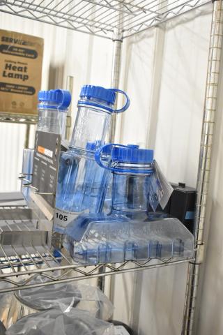 Six blue poly rapid cool bottles and drip tray on wire shelf. Bottles have blue lids and "Vigor Polar Paddle" marking. Auction lot 105.