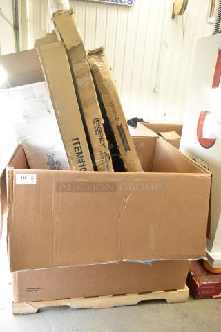 Large cardboard box on a pallet containing new, scratch and dent items including a table and wall shelf, visible shipping labels.