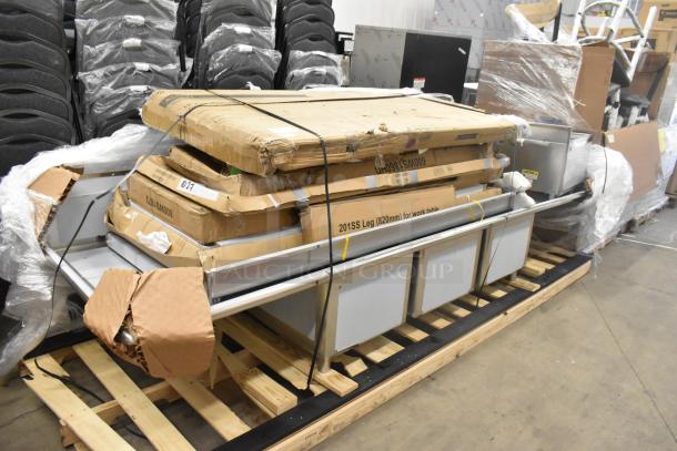 Stack of 12 new scratch and dent items including a shelf, work table, and stainless sink, on pallets. Labels indicate "201SS Leg (820mm) for work table."